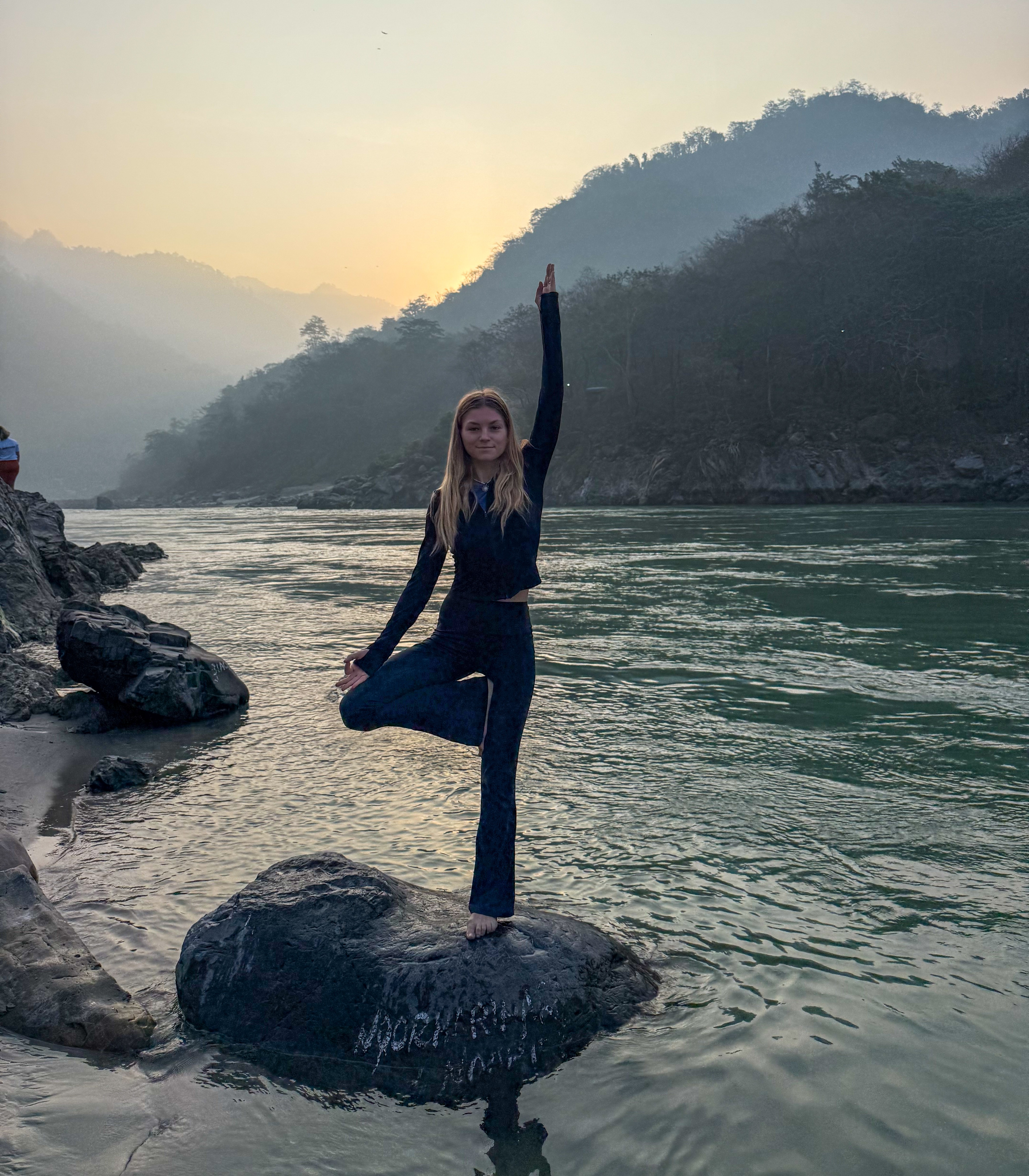 Sára practising yoga next to the Ganga in Rishikesh, India