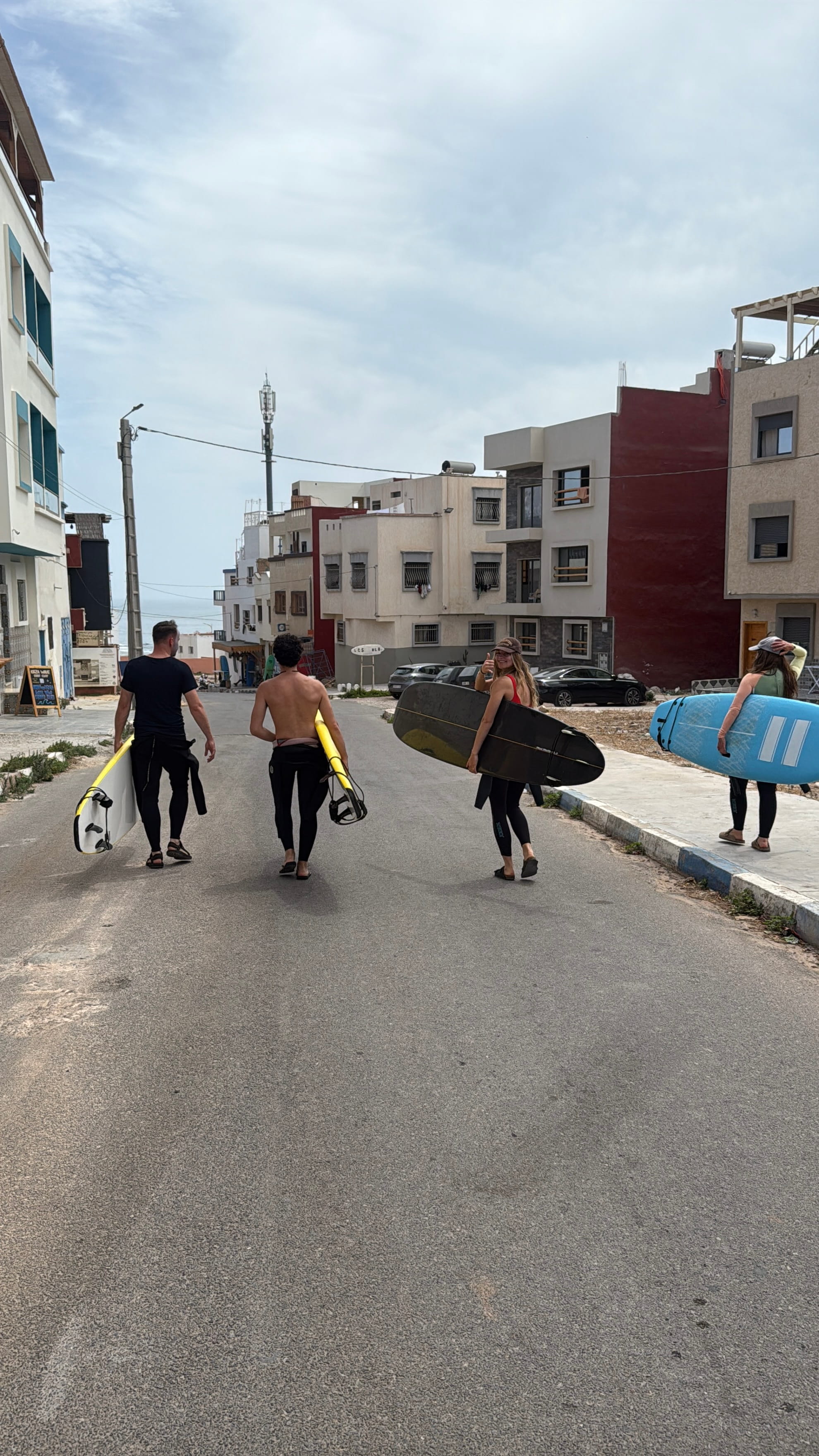 Surfers carrying boards down a village street in Imsouane on the way to the beach